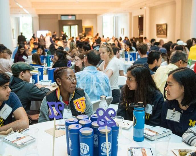 Partipicants in a mentorship program talking around a table at an event