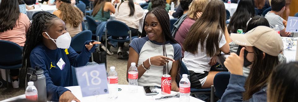 Group of students sitting around table smiling and talking