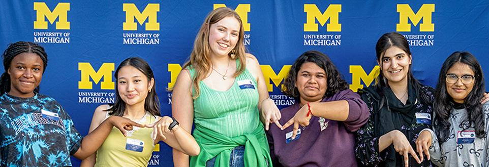 Group of students in front of backdrop with U-M logos.