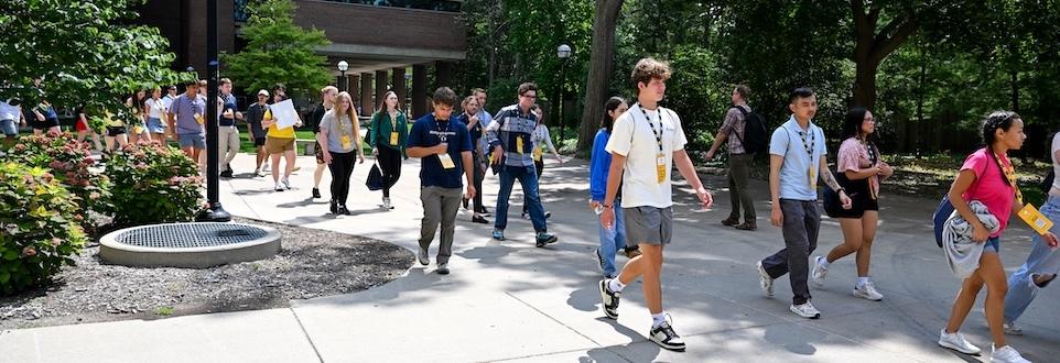 A large group of students tour campus during Orientation.
