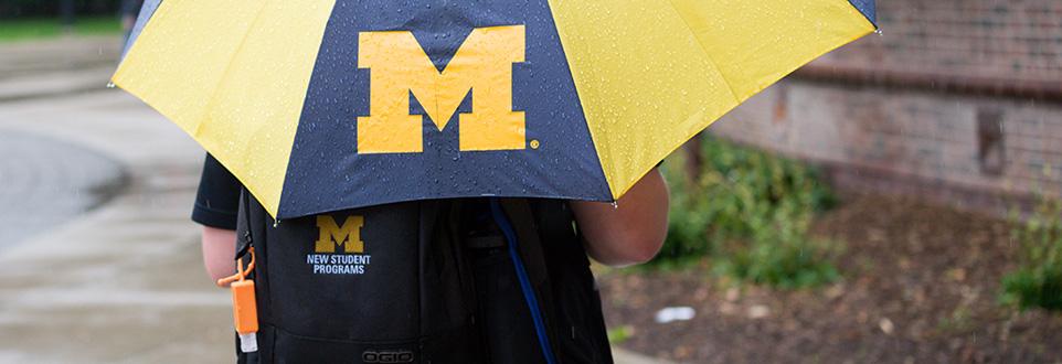 Student holding an M logo umbrella