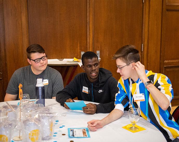 Three students sitting at a table together while doing an activity