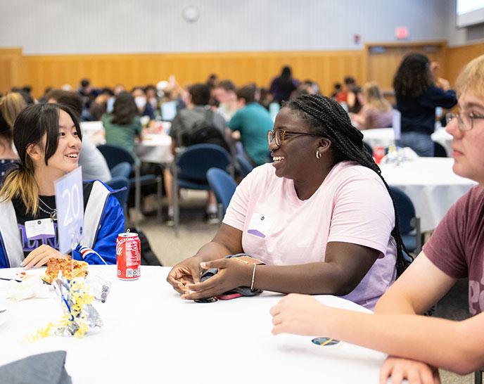 Students sitting at a table talking and smiling