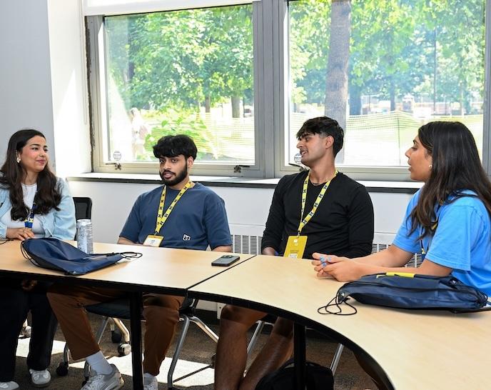 A group of students are seated at a table during Orientation